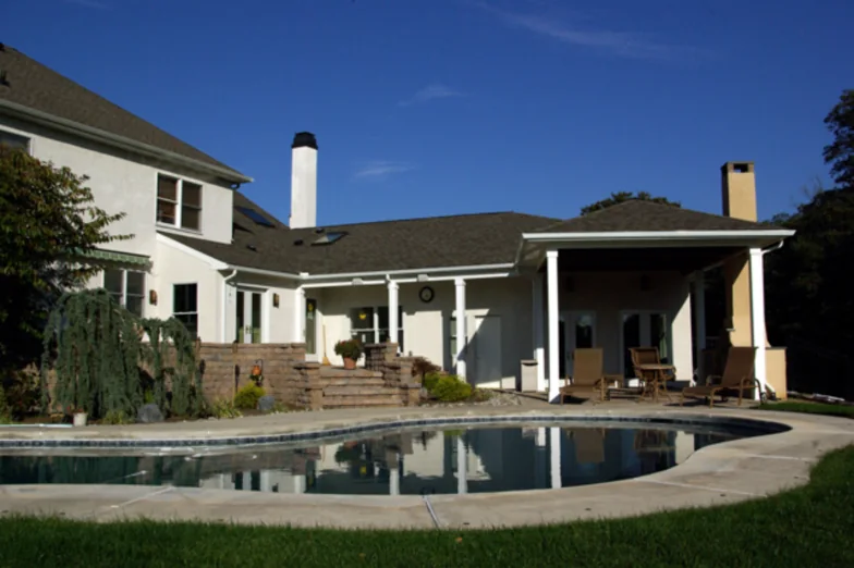 Stucco home with a covered outdoor room and in-law suite overlooking a pool