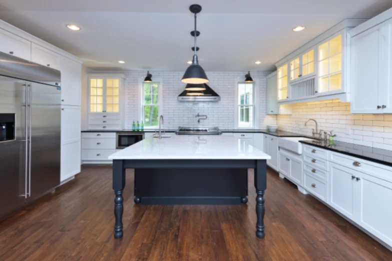 White farmhouse kitchen with a dark painted island, subway tile and black pendant lights
