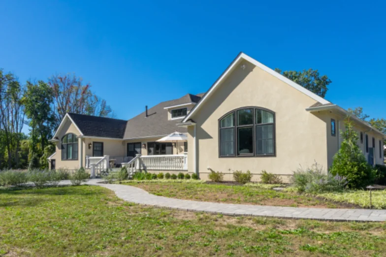 New stucco custom home with an arched window gable and paver walkway