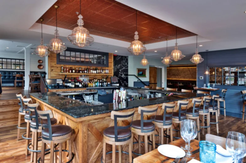 Restaurant bar with granite counter, reclaimed-wood bar front and glass pendant lights