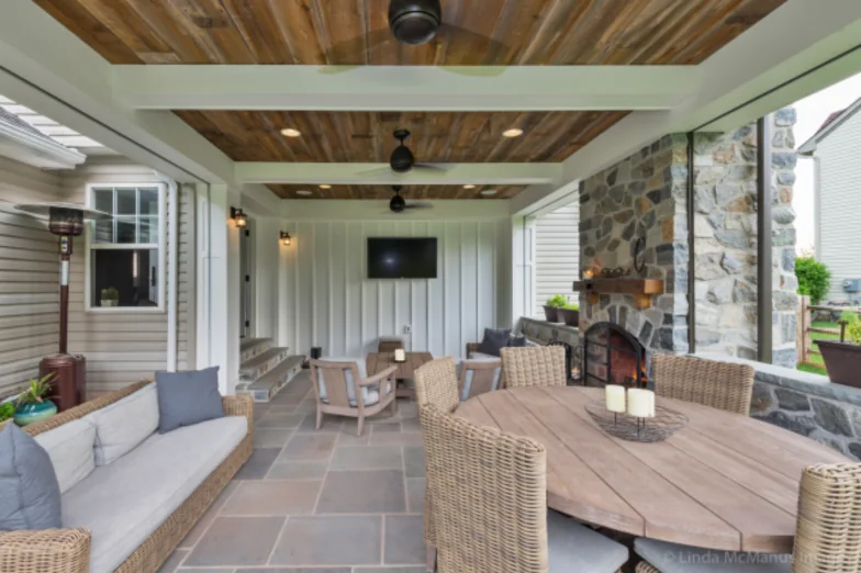 Covered outdoor room with a stone fireplace, reclaimed-wood ceiling and bluestone floor