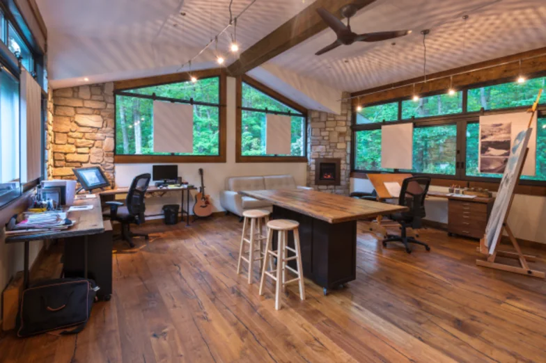Studio addition with timber beams, stone walls and a drafting table under tall windows